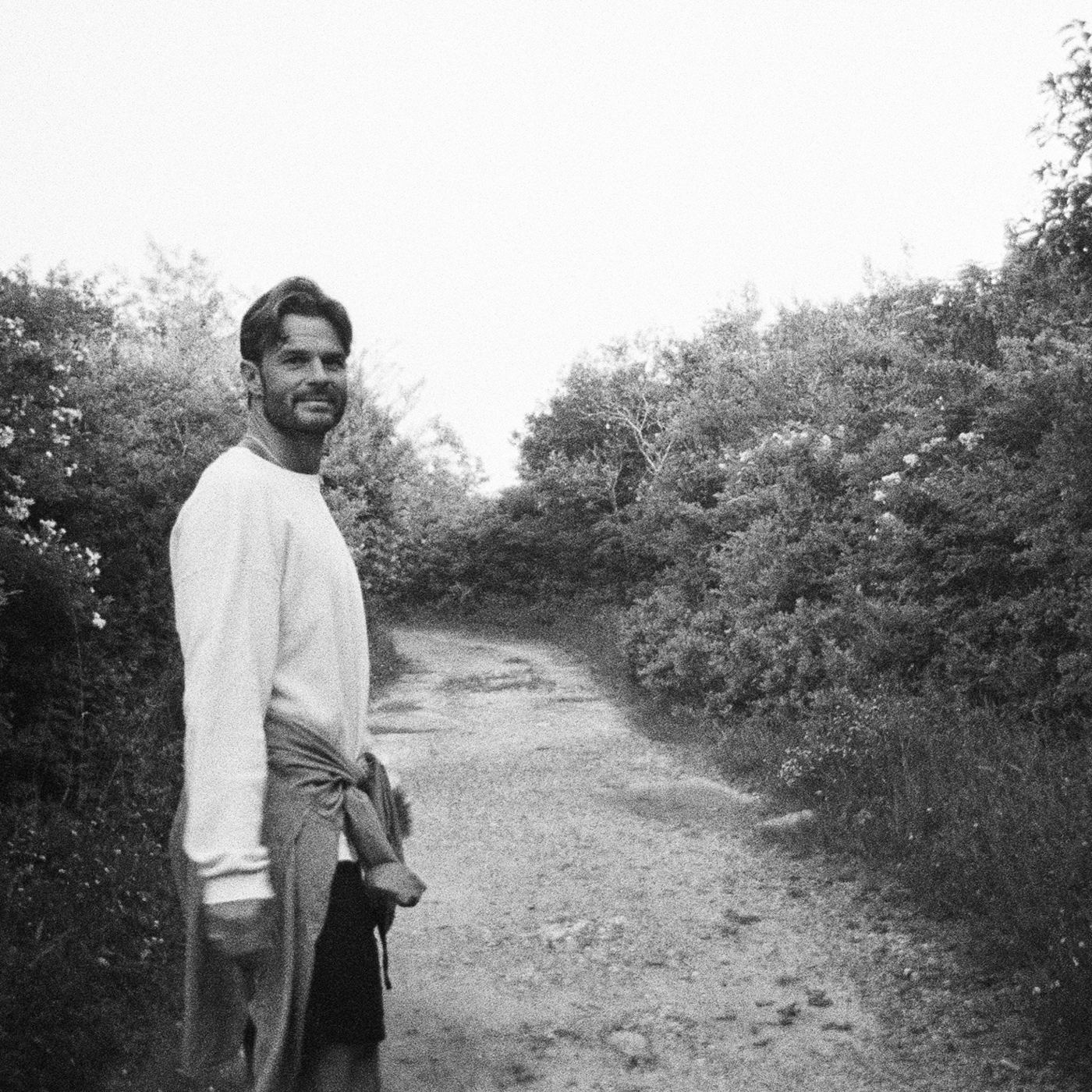 Flynn on a hedged dirt path, looking back over his shoulder, in black and white